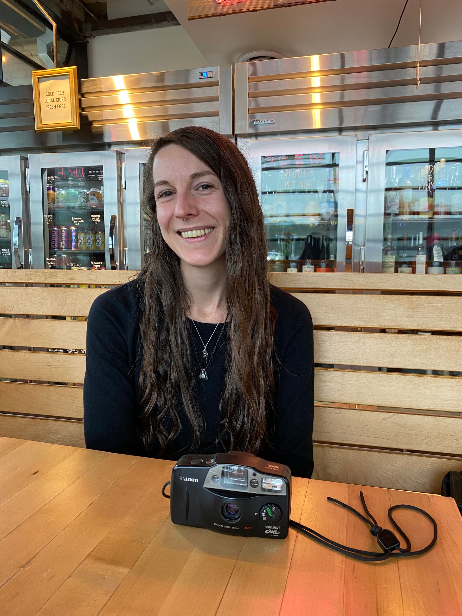 Smiling woman seated at a restaurant table with a camera in front of her