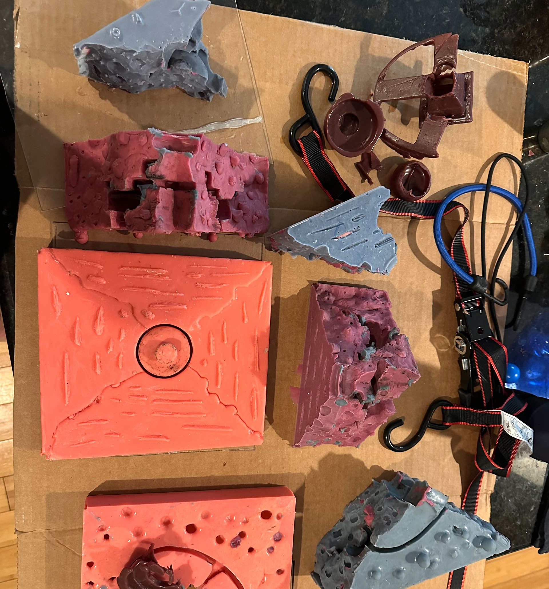 Pieces of a silicone mold arranged on a table with wax casting and bungee cords.