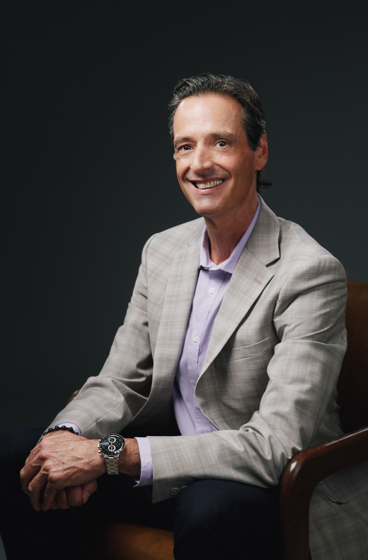 A man in a suit and blue shirt is standing with his hands in his pockets.