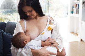 Woman breastfeeding a baby on a couch in a bright living room
