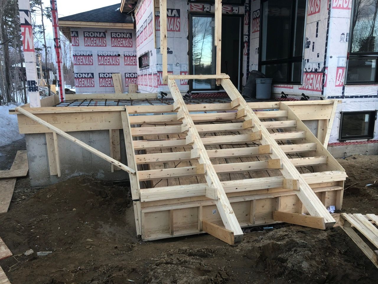 Une rampe en bois est en cours de construction devant une maison.
