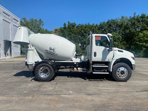 Un camion malaxeur à béton blanc est garé dans un parking.