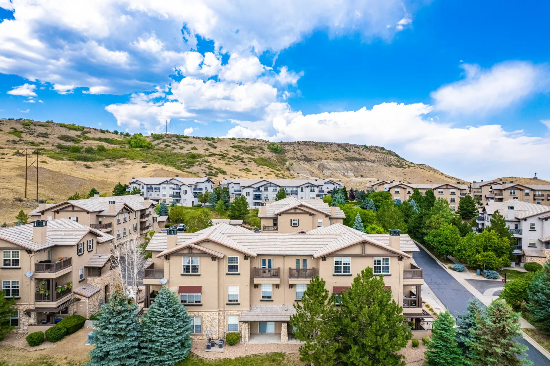 Aerial view of a beige apartment community with hills and a blue sky at Montrachet apartments in Lakewood, CO.