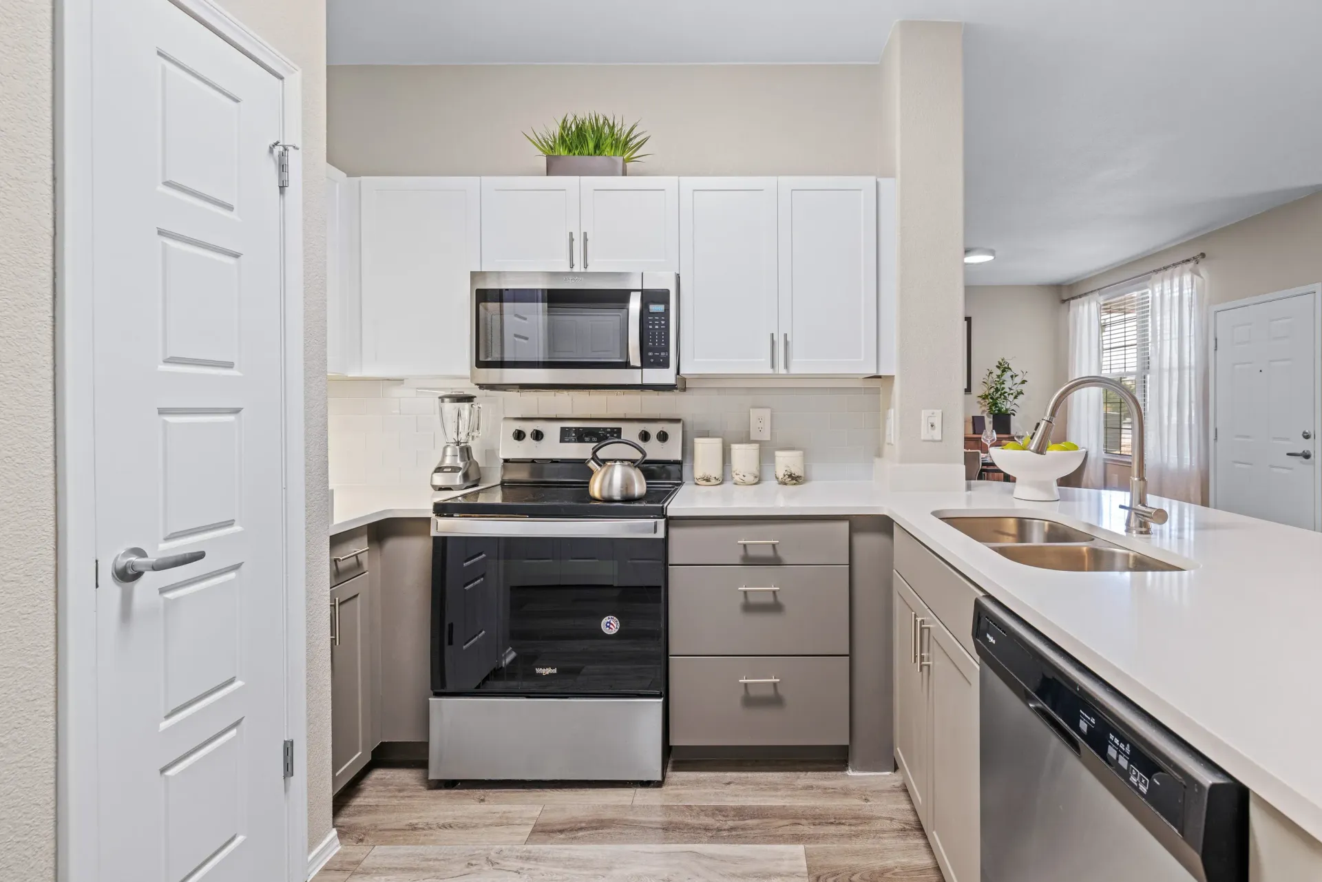 White kitchen with white cabinets, stainless steel appliances, and a double sink at Montrachet apartments in Lakewood, CO.