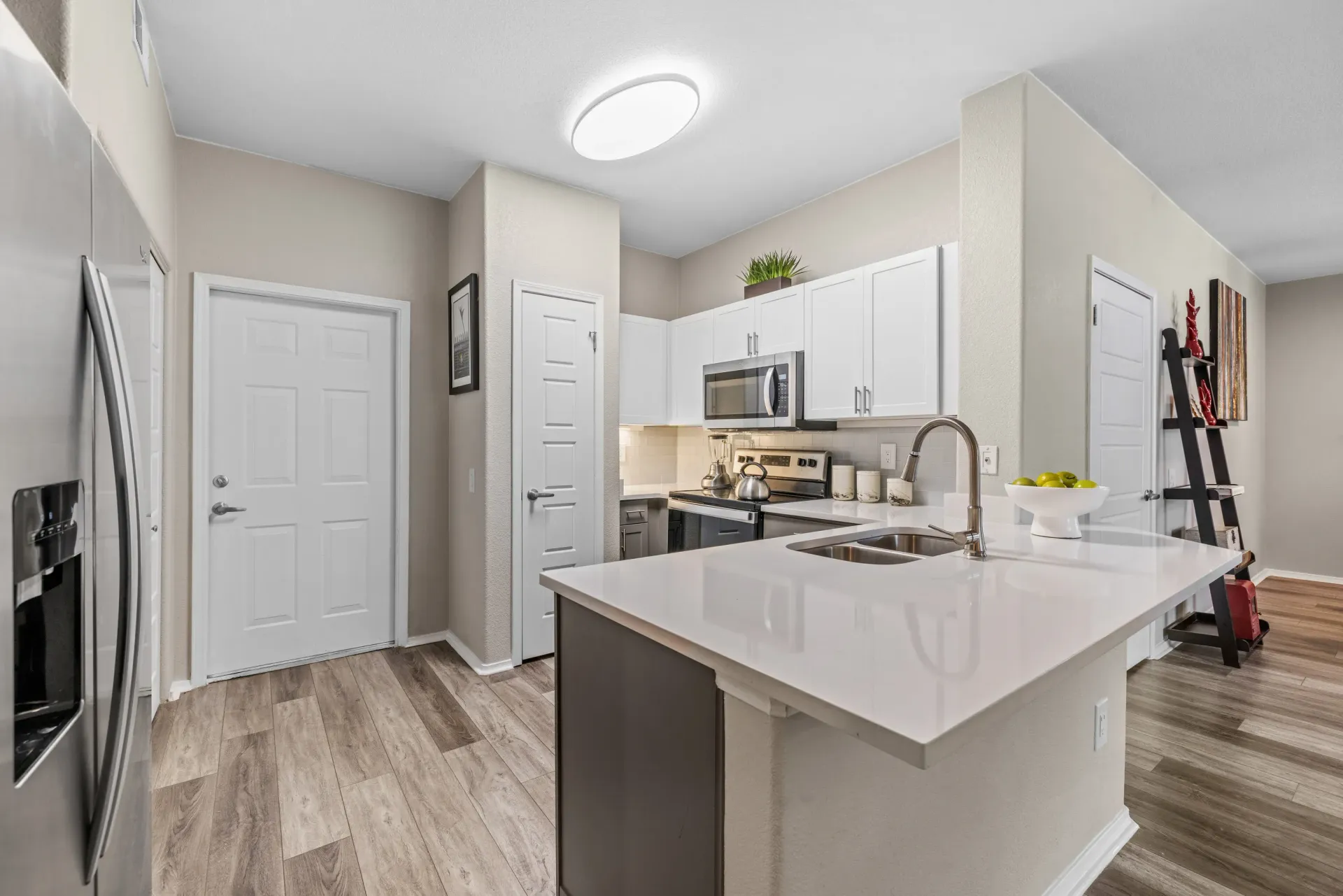 Open kitchen with white cabinets, stainless steel appliances, and a large island at Montrachet apartments in Lakewood, CO.