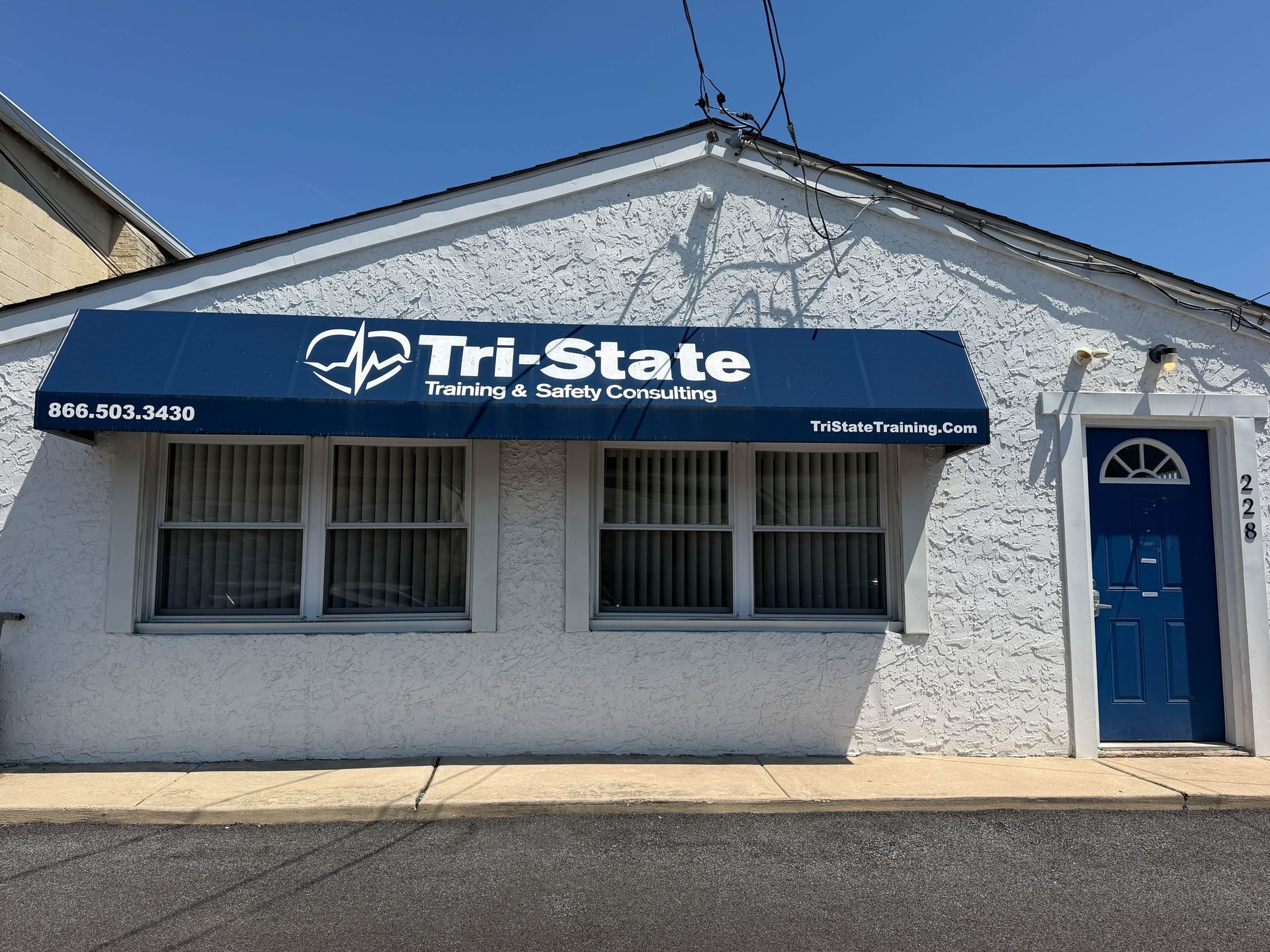 Tri-State Training & Safety Consulting storefront with blue awning and white stucco exterior
