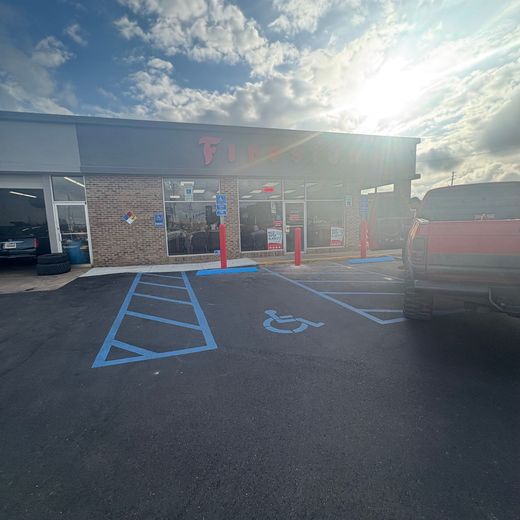 Storefront with blue handicap parking spaces and an accessible entrance under a bright cloudy sky