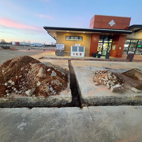 Small roadside building with an ice machine outside, flanked by dirt piles at dusk.