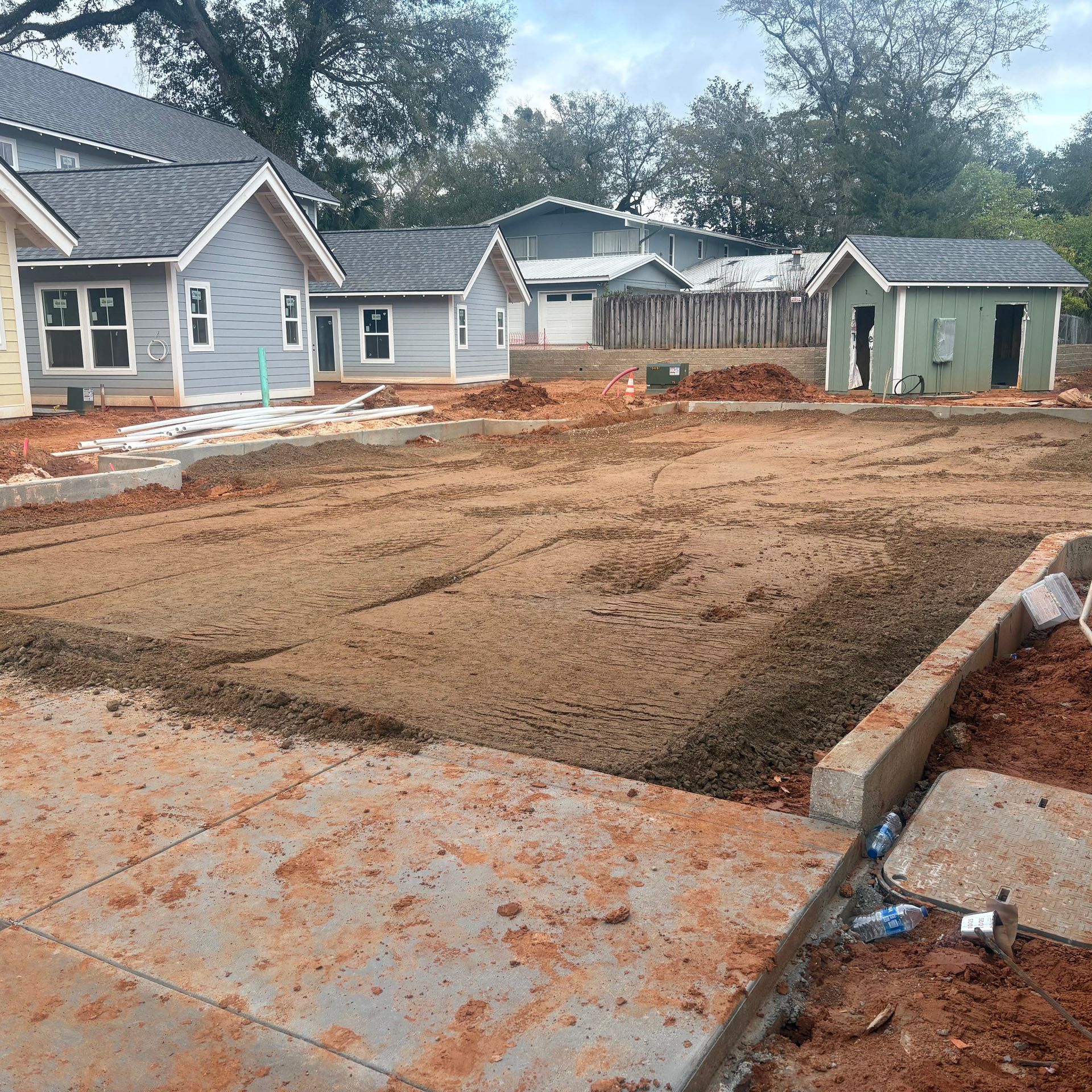 New house foundation pad leveled in a suburban construction site with nearby homes and dirt grading.