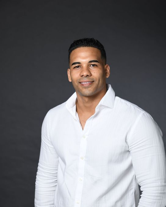 Portrait of a smiling person in a white shirt against a dark gray background