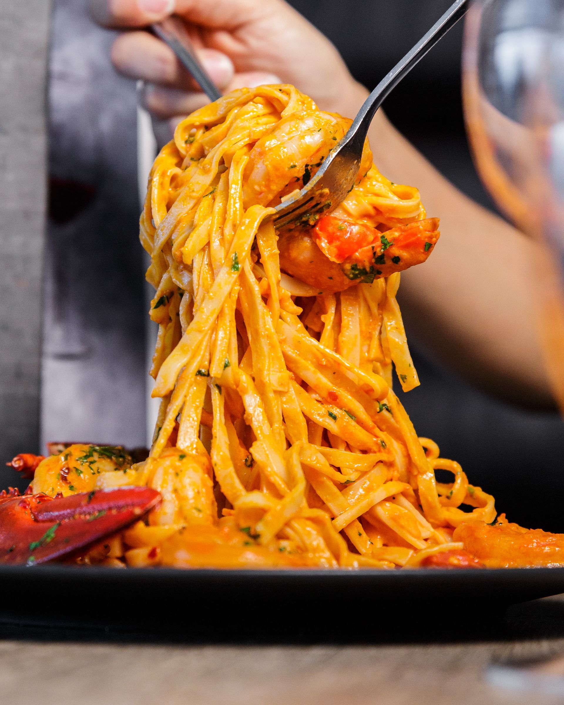 A person is eating spaghetti with shrimp on a plate with a fork.