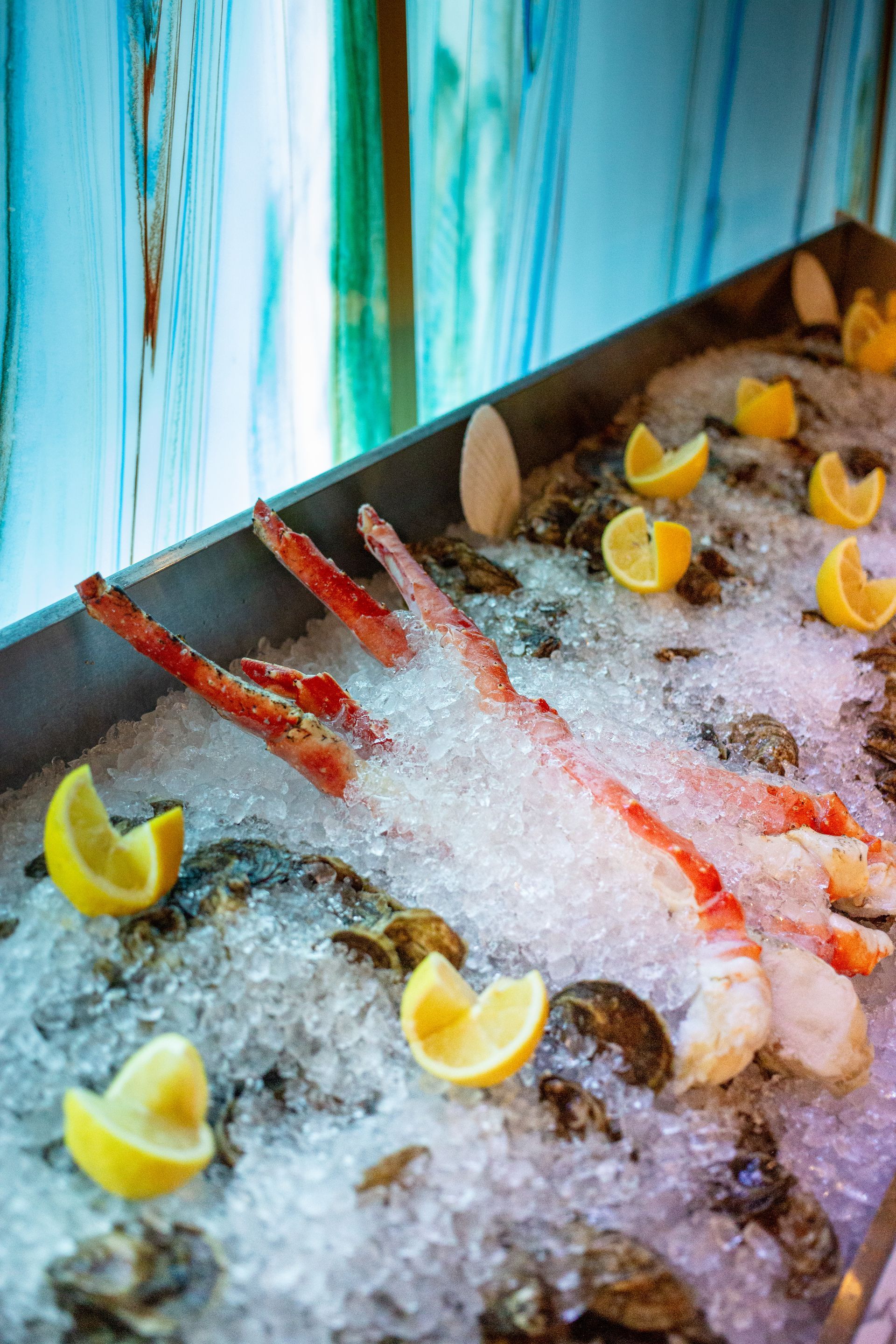 A tray of seafood on ice with lemon slices.