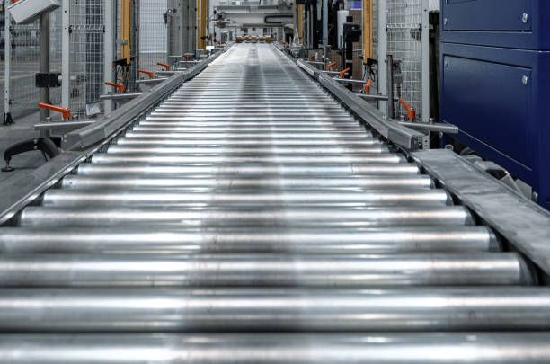 A conveyor belt in a factory with a lot of rollers on it.