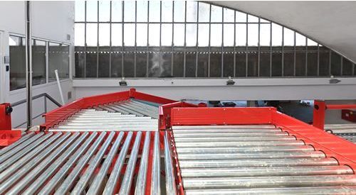 A conveyor belt in a factory with a window in the background.