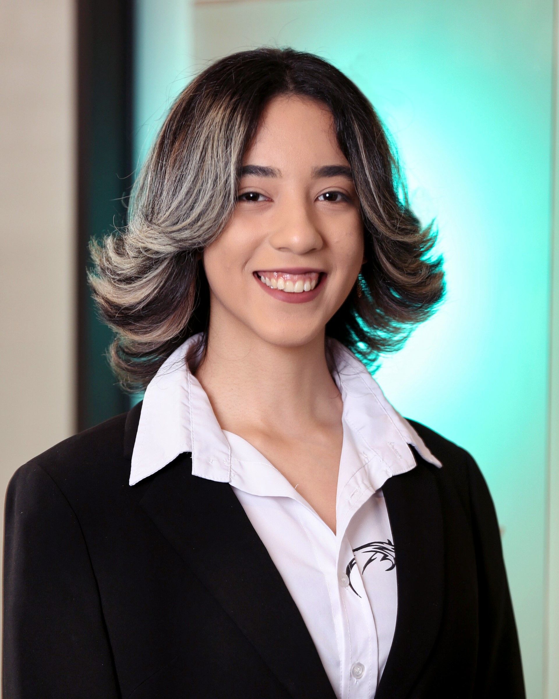 A woman in a suit and white shirt is smiling for the camera.