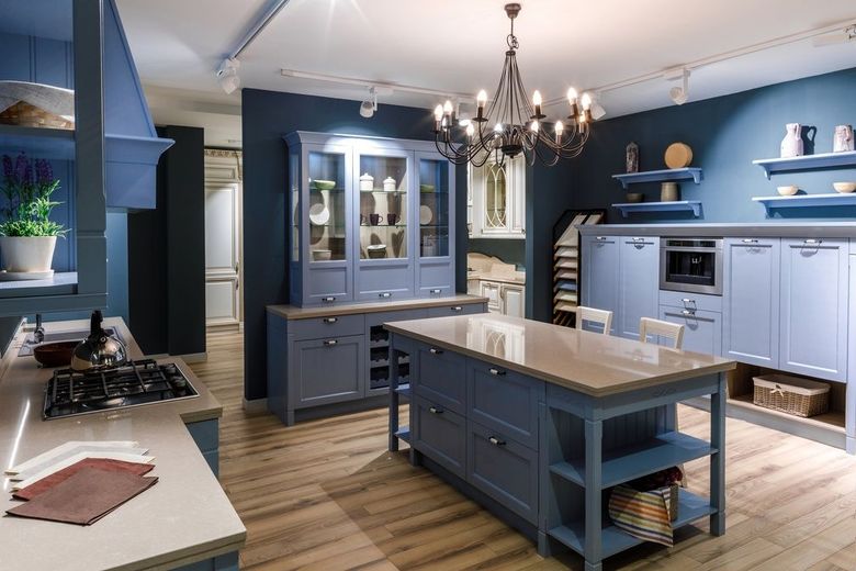 A kitchen with blue cabinets and a large island in the middle.