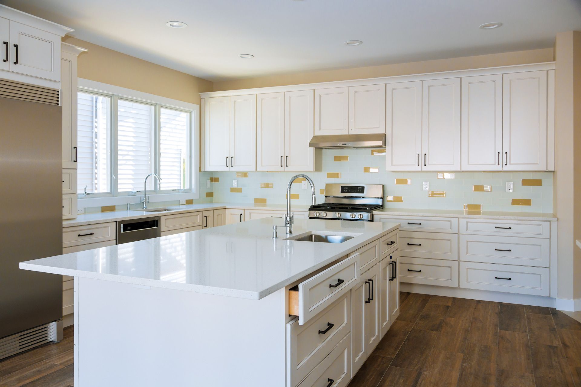 A kitchen with white cabinets, stainless steel appliances, and a large island.