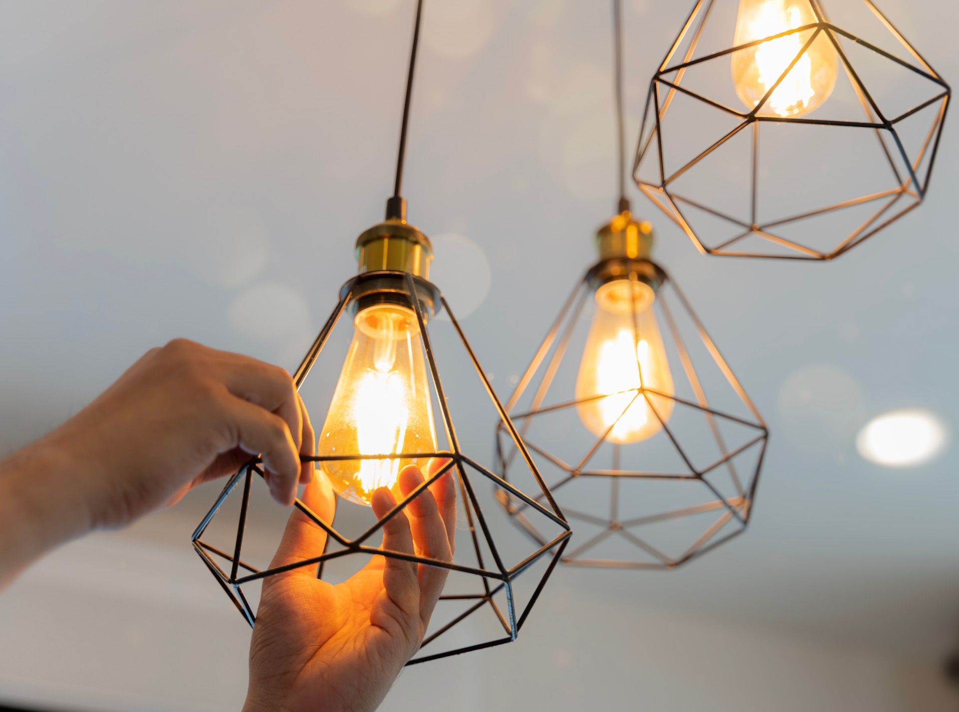 A person is holding a light bulb in a cage.