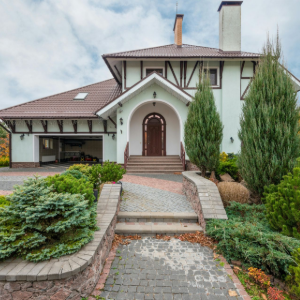 Large modern house with arched entry, stone walkway, and landscaped front garden