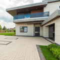 Modern house exterior with balcony, paved driveway, and small green lawn border