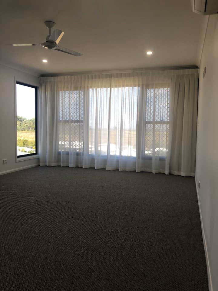 An Empty Living Room With a Ceiling Fan and Curtains — Whitsunday Vogue Interiors in Cannonvale, QLD