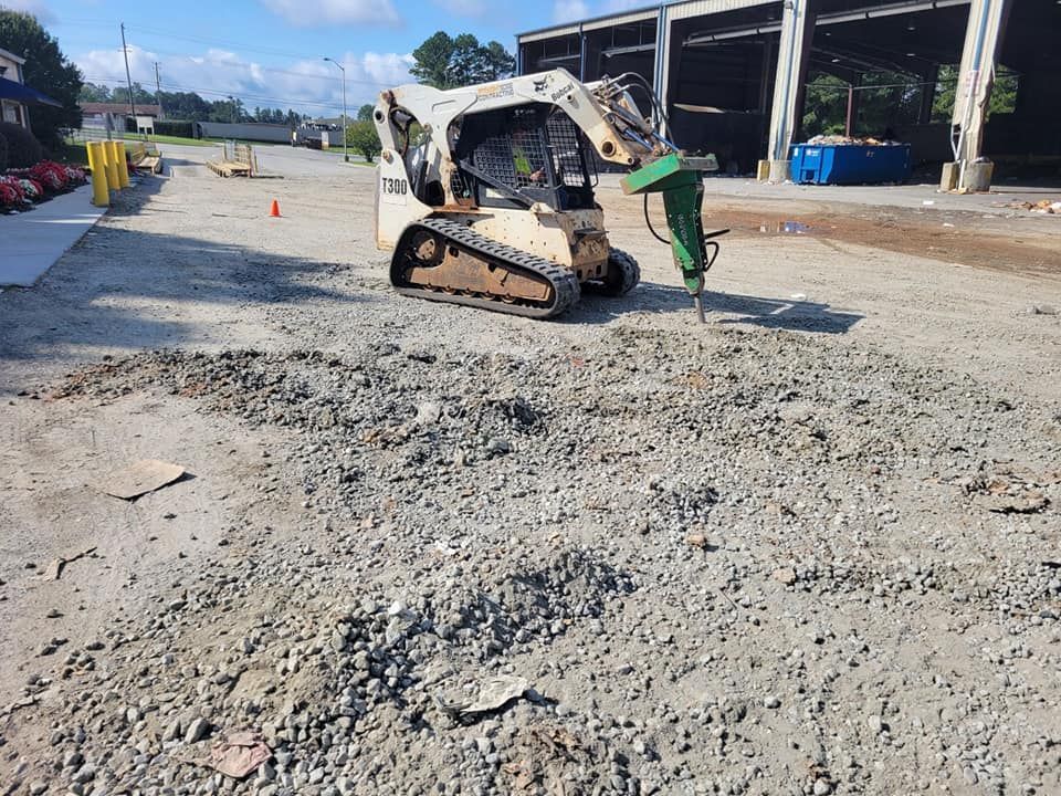 Worker guiding a compact track loader over a rough gravel surface at a construction site