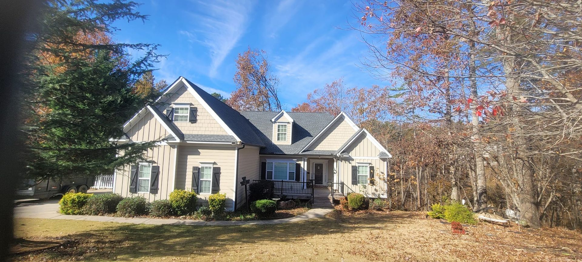 Large beige house with white trim and a front lawn in autumn sunlight