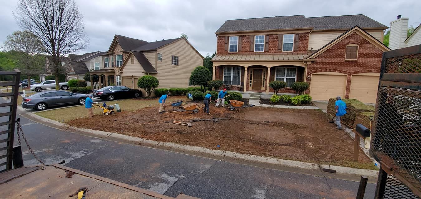 Suburban house front yard with fresh landscaping and workers near the driveway