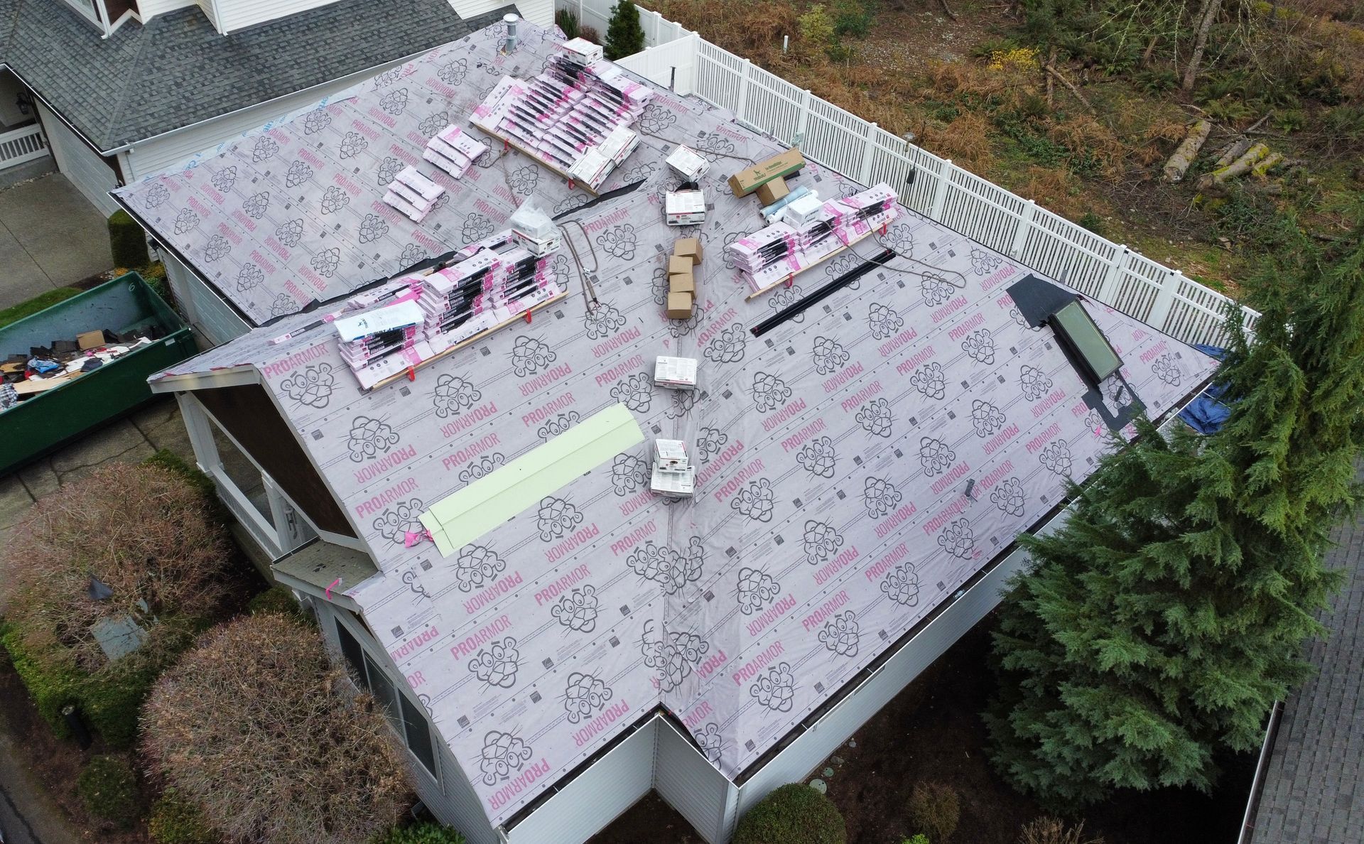 Aerial view of a roof with several workers and materials spread across it during repairs