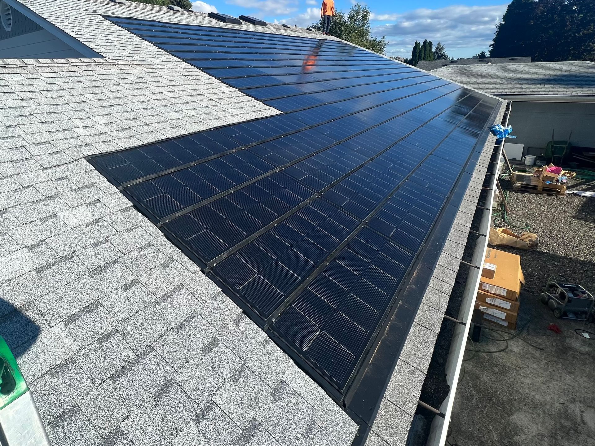 Solar panels installed on a sloped gray roof under a clear sky.