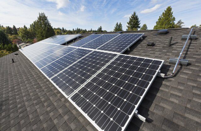Solar panels installed on a shingled rooftop under a clear sky