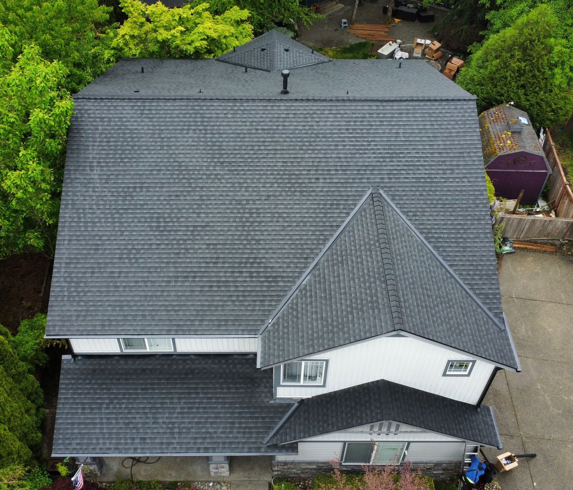 Aerial view of a gray-roofed house surrounded by trees and a driveway.