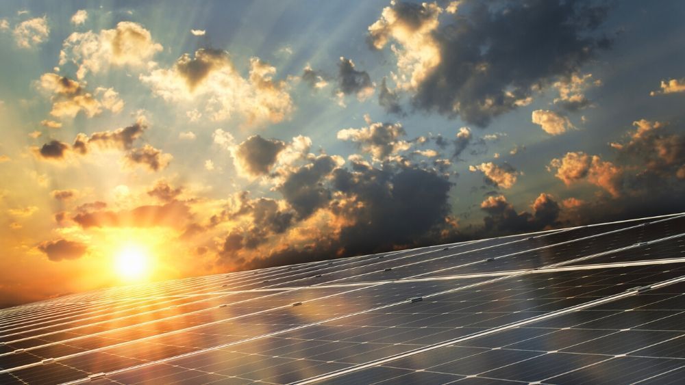 Solar panels at sunset under a cloud-filled sky