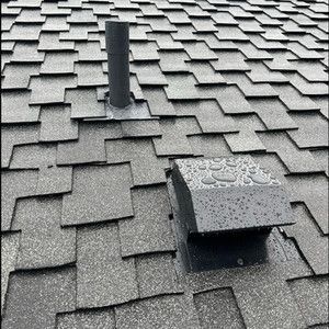 Gray shingle roof with two vents, including a square vent cover in the foreground