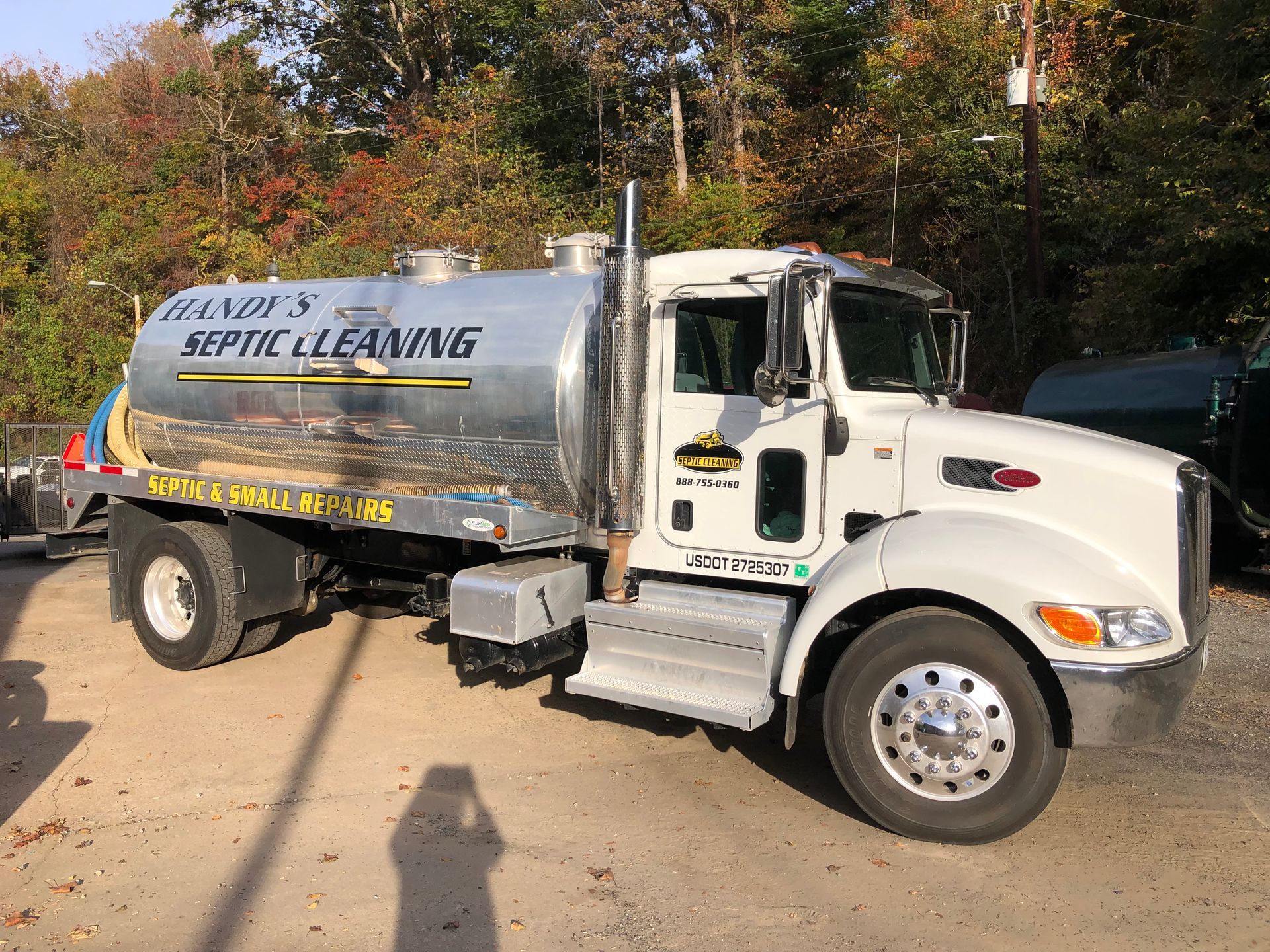 A white septic truck with a silver tank. 