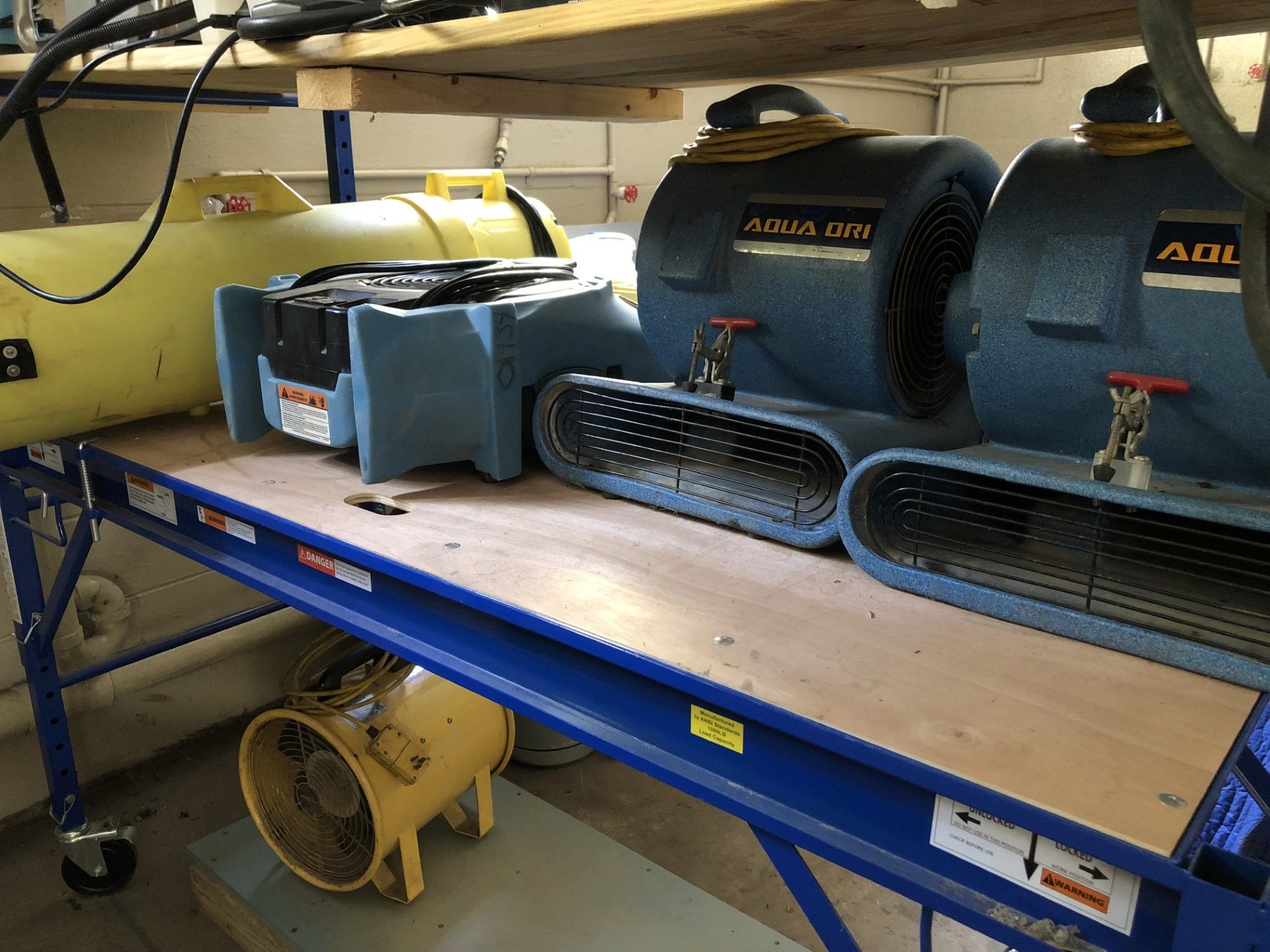 Fans and equipment on a blue work table, possibly for drying or ventilation.