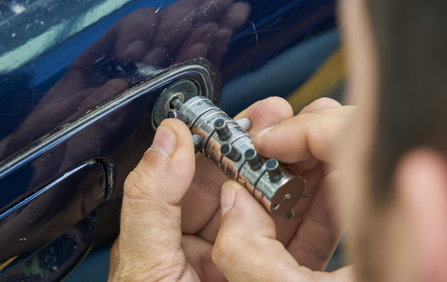 A man is using a key to open a car door.