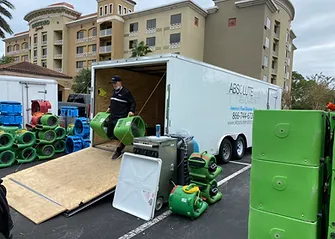 A man is loading equipment into a trailer in a parking lot.