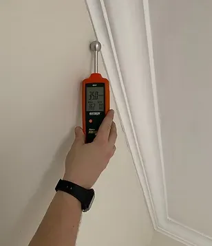 A person is using a digital thermometer to measure the humidity in a room.