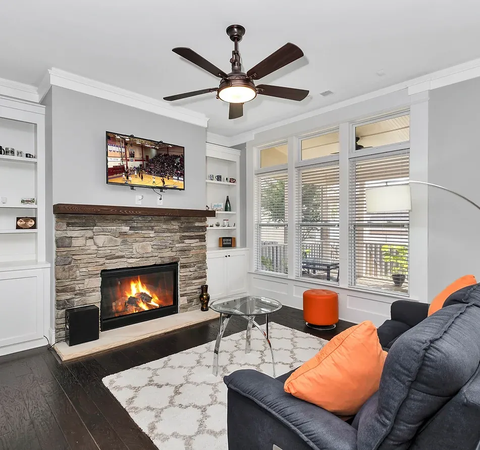 A living room with a fireplace and a ceiling fan