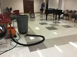 A vacuum cleaner is sitting on the floor of a room next to a piano.