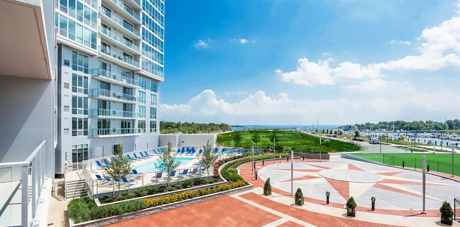 A large white apartment building with a swimming pool in front of it.