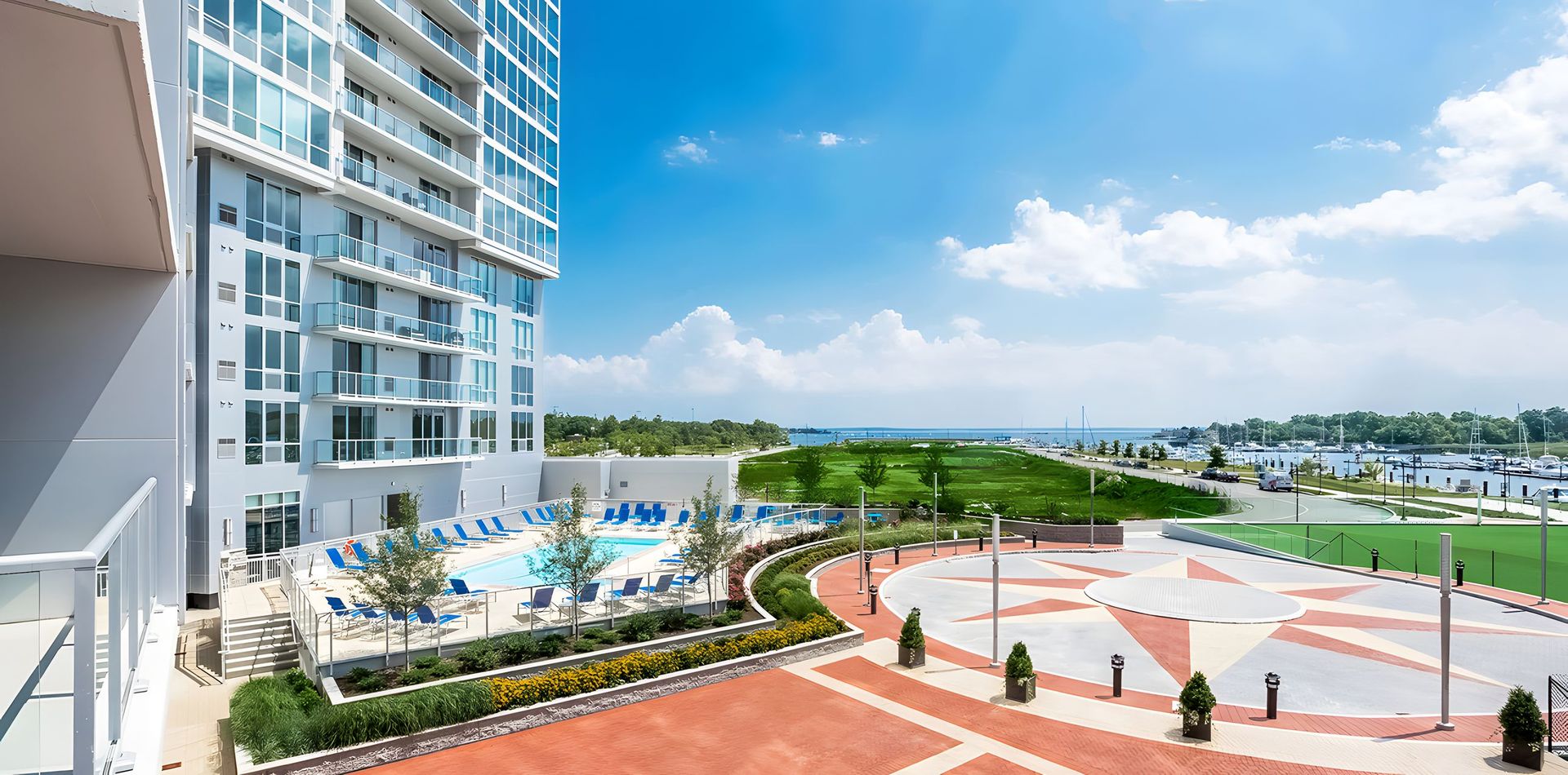 A large white apartment building with a swimming pool in front of it.