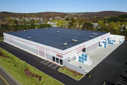 An aerial view of a large white building with a black roof.