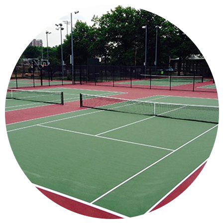 A tennis court in a circle with trees in the background