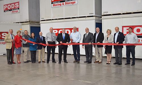 A group of people are standing next to each other cutting a red ribbon.