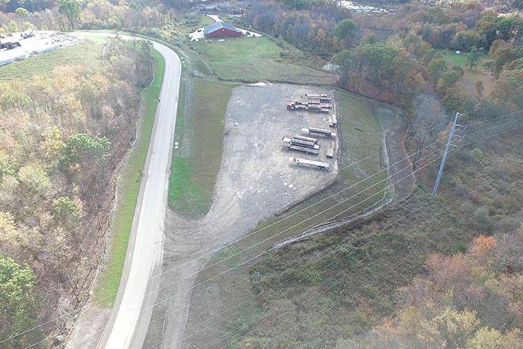 An aerial view of a dirt road going through a forest.