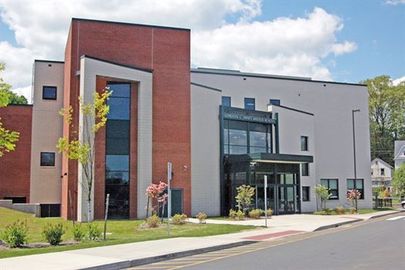 A large building with a lot of windows is sitting on the side of the road.