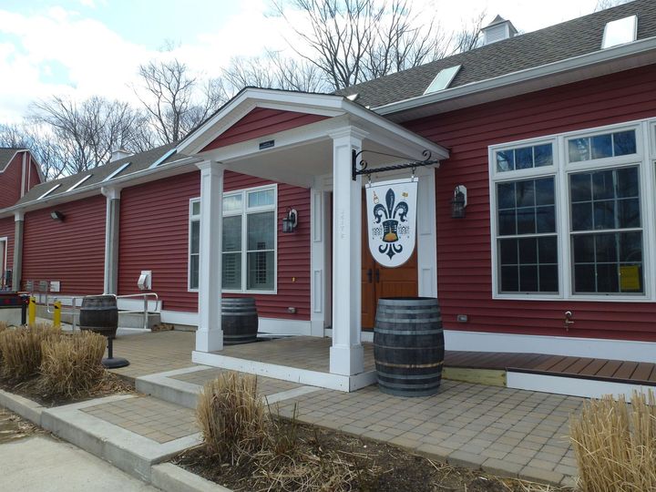 A red restaurant building with a white porch and barrels in front of it