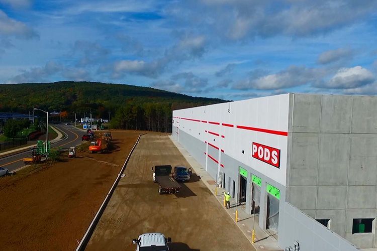 An aerial view of a warehouse under construction with trucks parked in front of it.